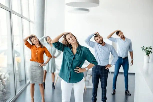 Equipo de trabajo realizando ejercicios de estiramiento en la oficina